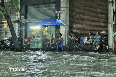 Người dân trên đường Ung Văn Khiêm, quận Bình Thạnh tạm dừng công việc buôn bán chờ nước rút. (Ảnh: Hồng Giang/TTXVN)