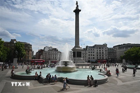 Người dân tránh nóng bên đài phun nước tại Quảng trường Trafalgar ở thủ đô London, Anh. (Ảnh: AFP/TTXVN)