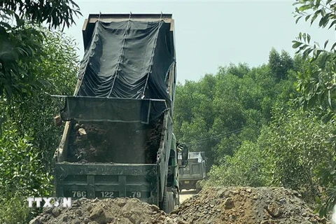 Một số đối tượng dùng xe tải chặn đầu, đổ đất bịt kín lối ra khỏi mỏ đất để uy hiếp phóng viên. (Ảnh: Lê Ngọc Phước/TTXVN)