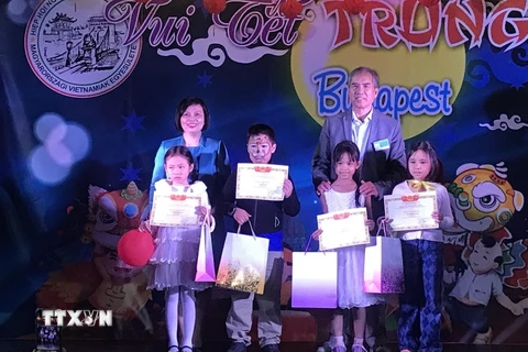 Đại sứ Việt Nam tại Hungary Nguyễn Thị Bích Thảo trao thưởng cho các cháu học sinh trong cộng đồng người Việt. (Ảnh: TTXVN phát)