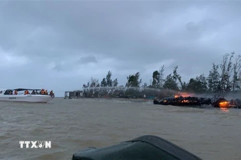 Lực lượng chức năng tại hiện trường khống chế đám cháy và di chuyển các thuyền tới khu vực an toàn. (Ảnh: Đoàn Hữu Trung/TTXVN)