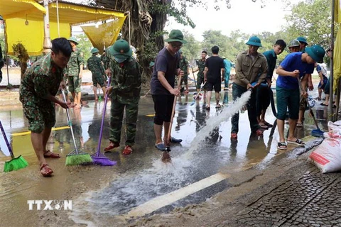 Các lực lượng tham gia dọn dẹp bùn non sau khi nước lũ rút tại nhiều tuyến đường của thành phố Huế. (Ảnh: Đỗ Trưởng/TTXVN)