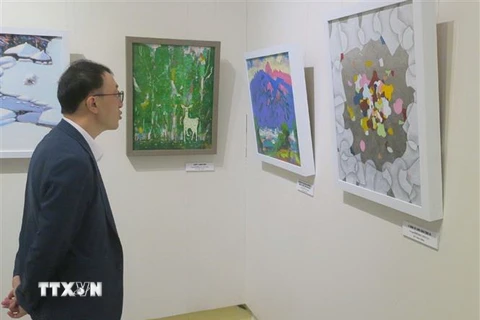 Du khách Hàn Quốc xem tranh trưng bày tại triển lãm. (Ảnh: TTXVN phát)