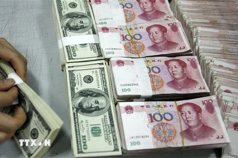 Nhân viên kiểm đồng USD (trái) và đồng nhân dân tệ tại một ngân hàng ở tỉnh An Huy, Trung Quốc. (Ảnh: AFP/TTXVN)