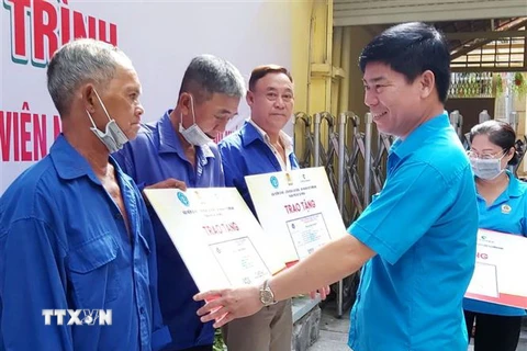 Ông Phạm Chí Tâm, Phó Chủ tịch Liên đoàn Lao động Thành phố Hồ Chí Minh trao tặng thẻ bảo hiểm y tế cho người lao động có hoàn cảnh khó khăn. (Ảnh: Thanh Vũ/TTXVN)