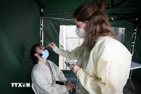 Nhân viên y tế lấy mẫu xét nghiệm COVID-19 cho người dân tại Paris, Pháp. (Ảnh: AFP/TTXVN)
