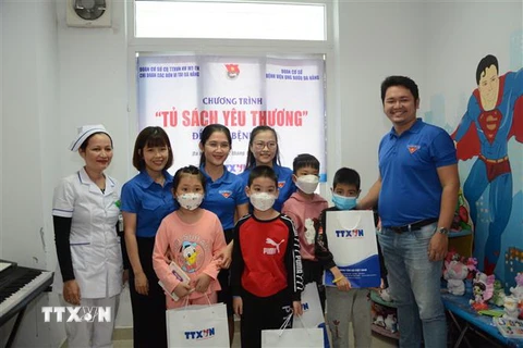 Đoàn viên thanh niên Cơ quan TTXVN khu vực miền Trung-Tây Nguyên trao tặng tủ sách yêu thương đến với các bệnh nhi Bệnh viện Ung bướu Đà Nẵng. (Ảnh: Văn Dũng/TTXVN)