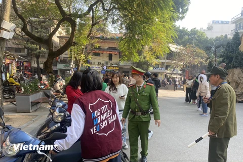 Công an phường Hàng Trống (Hoàn Kiếm) kiểm tra, nhắc nhở, xử lý phương tiện đỗ trái quy định trước đêm Noel. (Ảnh Mạnh Khánh/Vietnam+)