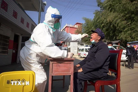 Nhân viên y tế lấy mẫu xét nghiệm COVID-19 cho người dân tại Quý Châu, Trung Quốc. (Ảnh: AFP/TTXVN)