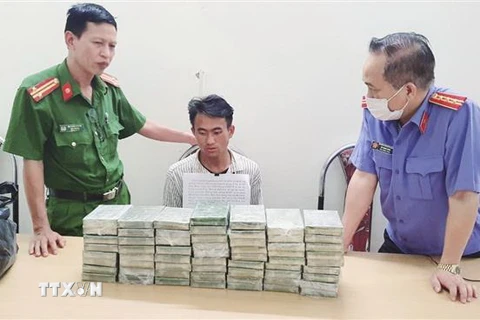 Đối tượng Chang A Sang trú tại bản Chuyên Gia 2, xã Nậm Kè, huyện Mường Nhé, tỉnh Điện Biên cùng tang vật 60 bánh heroin tại cơ quan điều tra. (Ảnh: TTXVN phát)