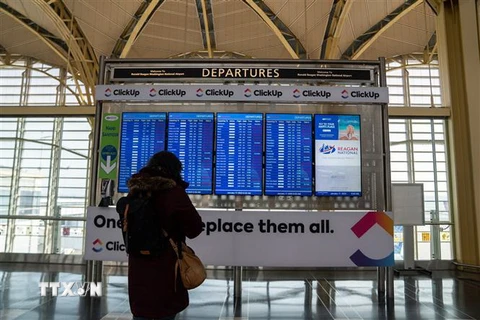 Hành khách xem thông tin về các chuyến bay tại sân bay Ronald Reagan. (Ảnh: THX/TTXVN)