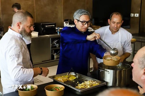 Đại sứ Việt Nam tại Israel Lý Đức Trung (áo xanh) cùng các đầu bếp làm món phở gà cho khách. (Ảnh: Vũ Hội/TTXVN)