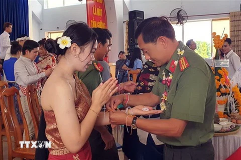 Nghi lễ buộc chỉ tay trong lễ đón Tết cổ truyền Bunpimay (Lào) được tổ chức ở Phân hiệu Đại học Đà Nẵng tại tỉnh Kon Tum. (Ảnh: Khoa Chương/TTXVN)