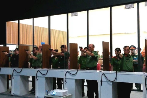 Các đại biểu thử nghiệm hệ thống bắn súng mô phỏng tại trường bắn điện tử. (Nguồn: Công an nhân dân)