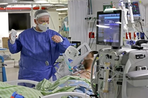 Nhân viên y tế điều trị cho bệnh nhân COVID-19. (Ảnh: AFP/TTXVN)