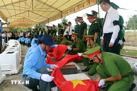 Lãnh đạo tỉnh Kiên Giang thực hiện nghi thức an táng hài cốt liệt sỹ. (Ảnh: Lê Sen/TTXVN)