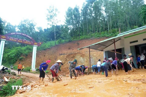 Người dân bản Nà Lếch, xã Chiềng Lao, huyện Mường La san gạt bùn, đất, đá bị sạt lở vào nhà. (Ảnh: Quang Quyết/TTXVN)