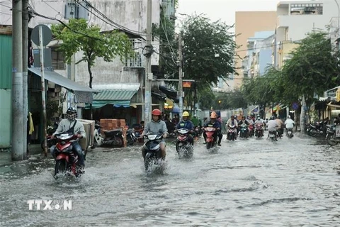 Người dân di chuyển giữa làn nước trên đường Huỳnh Tấn Phát ở quận 7. (Ảnh: Hồng Giang/TTXVN)