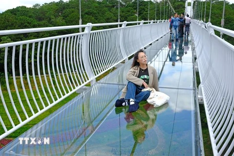 Một khách du lịch tạo dáng chụp hình 'sống ảo' trên cầu kính duy nhất ở Tây Nguyên. (Ảnh: Nguyễn Dũng/TTXVN)