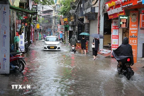 Người dân phố Triều Khúc ở Hà Nội đi lại khó khăn do mưa ngập. (Ảnh: Hoàng Hiếu/TTXVN)