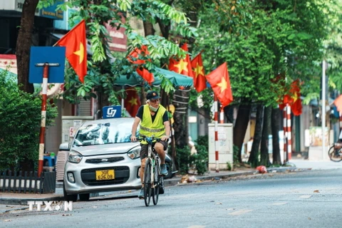 Người dân thư thái đạp xe qua những con phố rực đỏ cờ Tổ quốc trong ngày Quốc khánh. (Ảnh: Phạm Tuấn Anh/TTXVN)
