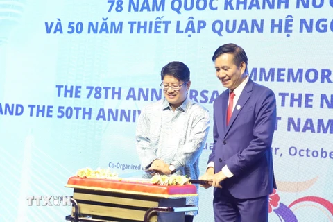 Đại sứ Đinh Ngọc Linh và Bộ trưởng Bộ Hợp tác và Phát triển Doanh nghiệp Malaysia Ewon Benedick tiến hành nghị thức cắt bánh chúc mừng. (Ảnh: An Nguyễn/TTXVN)