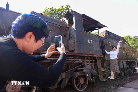 Người dân chụp ảnh tại đầu máy xe lửa hơi nước Tự Lực được trưng bày trong khuôn khổ Lễ hội Thiết kế Sáng tạo Hà Nội 2023. (Ảnh: Tuấn Đức/TTXVN)