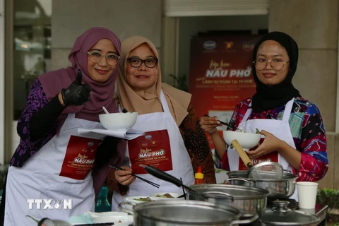 Thành viên các Cơ quan Ngoại giao tại Thành phố Hồ Chí Minh thưởng thức món phở sau khi hoàn thành lớp học nấu phở. (Ảnh: Thanh Vũ/TTXVN