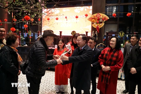 Chủ tịch UBND tỉnh Quảng Ninh Cao Tường Huy (thứ 2 bên phải) tặng hoa và lì xì cho du khách. (Ảnh: Đức Hiếu/TTXVN)