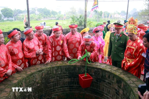 Các cụ cao niên thực hiện nghi thức lấy nước từ giếng Rồng. (Ảnh: Nguyễn Lành/TTXVN)