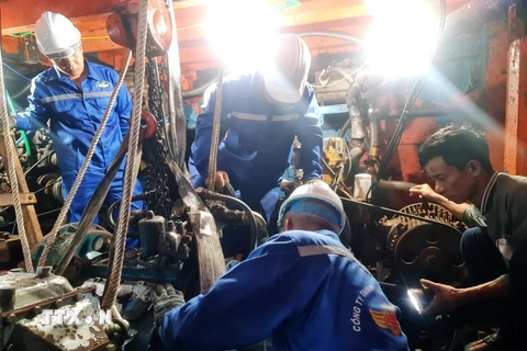 Cán bộ kỹ thuật Trung tâm Dịch vụ Hậu cần-Kỹ thuật đảo Trường Sa tích cực sửa chữa sự cố máy tàu cho ngư dân. (Ảnh: TTXVN phát)