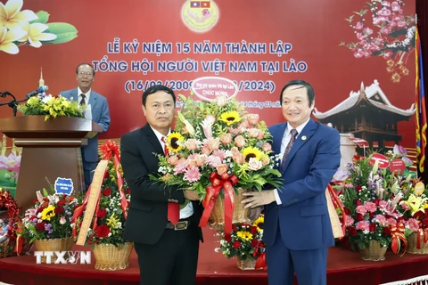 Đại sứ Việt Nam tại Lào Nguyễn Bá Hùng tặng hoa chúc mừng 15 năm thành lập Tổng hội. (Ảnh: Phạm Kiên/TTXVN)