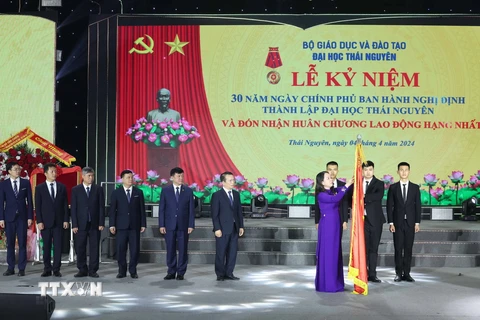 Quyền Chủ tịch nước Võ Thị Ánh Xuân gắn Huân chương Lao động hạng Nhất lên cờ truyền thống của Đại học Thái Nguyên. (Ảnh: Thống Nhất/TTXVN)