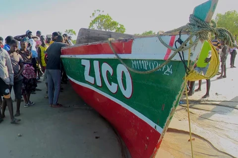 Một số người đứng cạnh chiếc thuyền mà truyền thông địa phương cho biết đã bị lật ngoài khơi tỉnh Nampula của Mozambique. (Nguồn: AP)