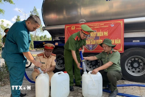 Cán bộ, chiến sỹ Phòng Cảnh sát Giao thông Công an tỉnh Bến Tre cùng các đơn vị liên quan cấp nước ngọt cho người dân. (Ảnh: TTXVN phát)