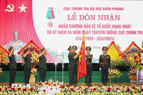 Trung tướng Nguyễn Anh Tuấn, Chính Ủy Bộ đội biên phòng gắn Huân chương Bảo vệ Tổ quốc hạng Nhất lên Cờ truyền thống của Cục Chính trị Bộ đội biên phòng. (Ảnh: Trọng Đức/TTXVN)