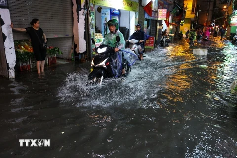 Người dân di chuyển khó khăn khi đi qua đoạn ngập sau một trận mưa lớn. (Ảnh: Tuấn Anh/TTXVN)
