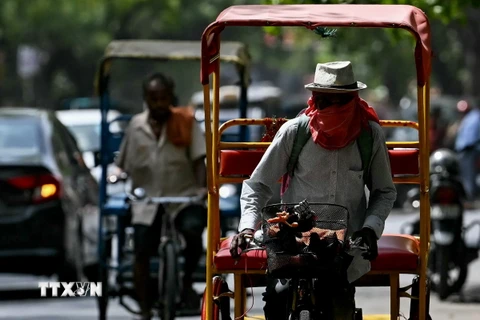 Người dân đội mũ và khăn để tránh nắng nóng tại New Delhi, Ấn Độ. (Ảnh: AFP/TTXVN)