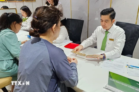 Khách hàng mua vàng miếng thực hiện giao dịch tại Ngân hàng Vietcombank ở Thành phố Hồ Chí Minh. (Ảnh: Thanh Vũ/TTXVN)