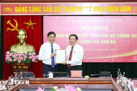 Ông Phan Đình Trạc, Ủy viên Bộ Chính trị, Bí thư Trung ương Đảng, Trưởng Ban Nội chính Trung ương trao Quyết định của Bộ Chính trị cho ông Nguyễn Hữu Đông. (Ảnh: Phương Hoa/TTXVN)