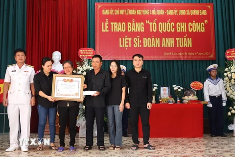 Đại diện Chỉ huy Lữ đoàn 682 (ngoài cùng bên trái) trao Bằng 'Tổ quốc ghi công' cho gia đình Liệt sỹ Đoàn Anh Tuấn. (Ảnh: TTXVN phát)