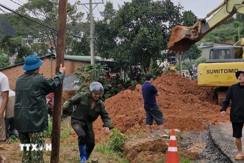 Lực lượng chức năng cùng thiết bị cơ giới triển khai công tác cứu hộ, giải tỏa hiện trường. (Ảnh: TTXVN phát)