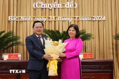 Bí thư Tỉnh ủy Bắc Ninh Nguyễn Anh Tuấn (bên trái) tặng hoa chúc mừng Chủ tịch Hội đồng Nhân dân tỉnh khóa XIX, nhiệm kỳ 2021-2026 Nguyễn Hương Giang. (Ảnh: Thái Hùng/TTXVN)