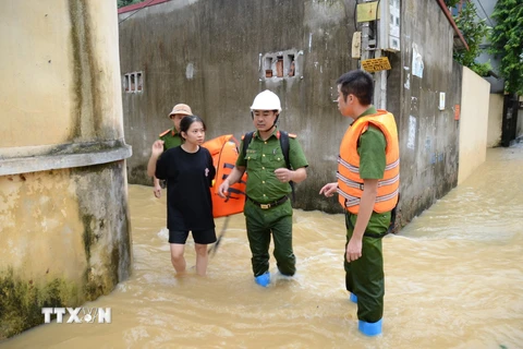 Lực lượng chức năng hỗ trợ người dân đến nơi an toàn. (Ảnh: Đỗ Huyền/TTXVN)