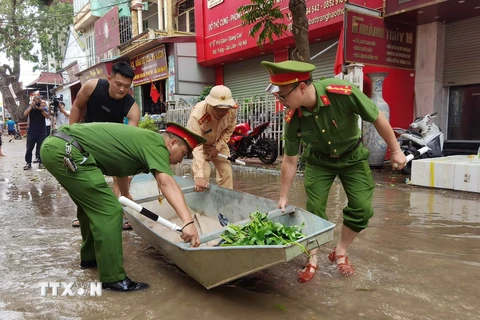 Lực lượng công an hỗ trợ thuyền nhỏ để giúp người dân di chuyển trong vùng lụt. (Ảnh: Thanh Tùng/TTXVN)