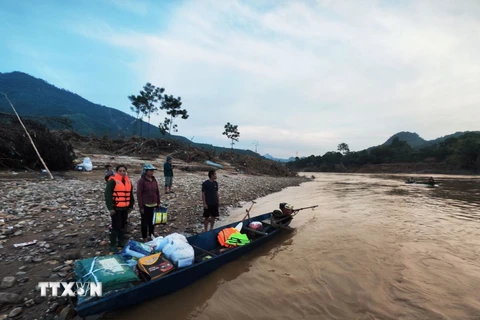 Các tình nguyện viên di chuyển bằng xuồng đến trao hỗ trợ cho người dân bản Cuông 2. (Ảnh: Phùng Nam Sương/TTXVN)