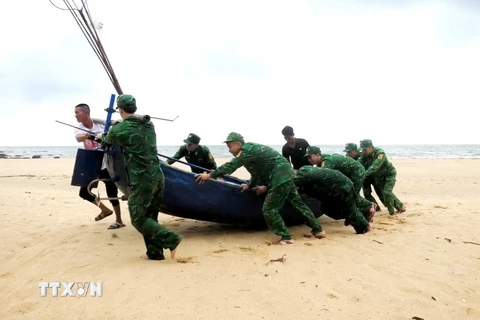 Cán bộ, chiến sỹ Đồn Biên phòng Lý Hòa (Bộ đội Biên phòng Quảng Bình) giúp ngư dân xã Đức Trạch, huyện Bố Trạch, tỉnh Quảng Bình đưa thuyền lên bờ tránh trú. (Ảnh: TTXVN phát)