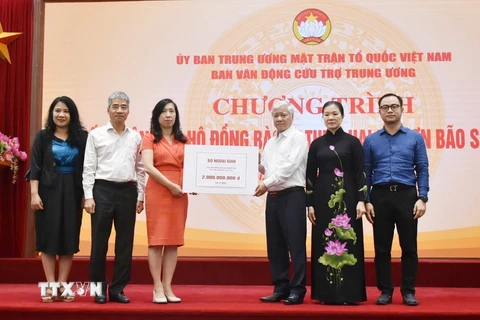 Chủ tịch Ủy ban Trung ương Mặt trận Tổ quốc Việt Nam Đỗ Văn Chiến tiếp nhận bảng tượng trưng số tiền từ Thứ trưởng Bộ Ngoại giao, Chủ nhiệm Ủy ban Nhà nước về người Việt Nam ở nước ngoài Lê Thị Thu Hằng. (Ảnh: TTXVN phát)