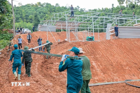 Lực lượng bộ đội, dân quân tự vệ hỗ trợ chuyển vật liệu xây dựng vào khu vực thi công xây lắp nhà tạm cho người dân Làng Nủ. (Ảnh: Hoàng Hiếu/TTXVN)