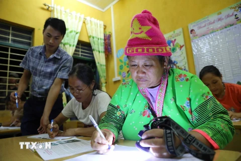 Chị Vàng Thị Của (phải) ở bản Cà Là Pá, xã Leng Su Sìn, tuy không phải là học viên chính thức nhưng vẫn xin tự nguyện đi học xóa mù chữ. (Ảnh: Trung Kiên/TTXVN)